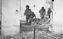 Four British paratroopers moving through a shell-damaged house in Oosterbeek during Operation Market Garden